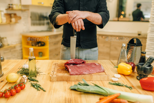 Male person with knife and piece of raw meat