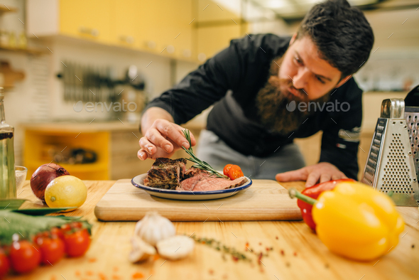 Chef decorates herbs roasted meat slices in plate - Stock Photo - Images