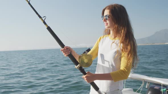 Side view of a teenage Caucasian girl fishing on boat, Stock Footage