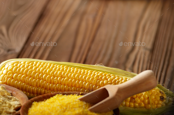 Bowl of corn grits corncob and corn flour on kitchen table