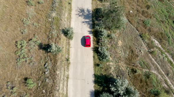 a Red Passenger Car Drives on a Shroud on a Concrete Road