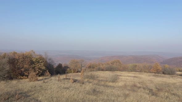 Autumnal landscape with forest over hill in Eastern Serbia 4K aerial footage alt