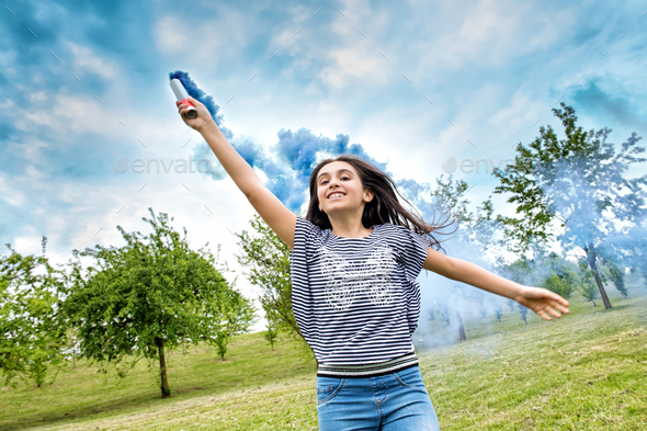 Happy laughing young girl trailing a smoke flare