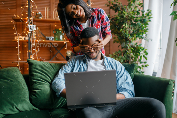 Black couple with laptop having fun on sofa