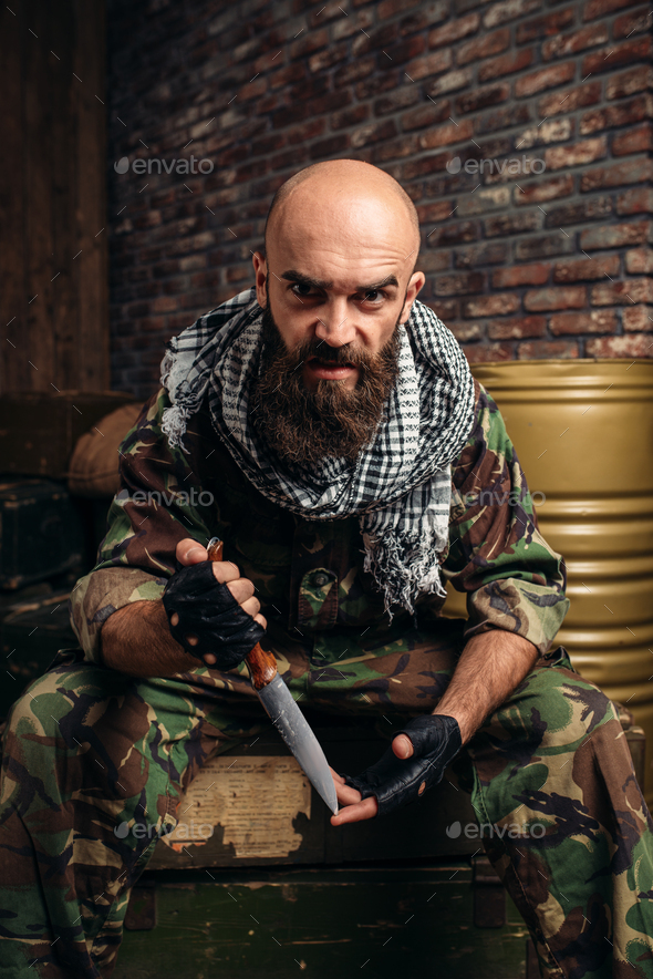 Terrorist with knife sits on boxes of ammunition - Stock Photo - Images