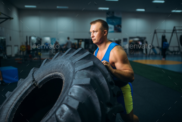 Athlete doing exercise with truck tyre, crossfit