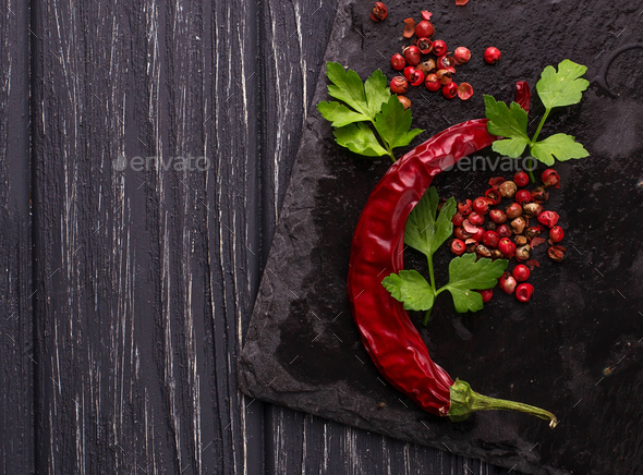 Chili peppers and rose pepper on slate background