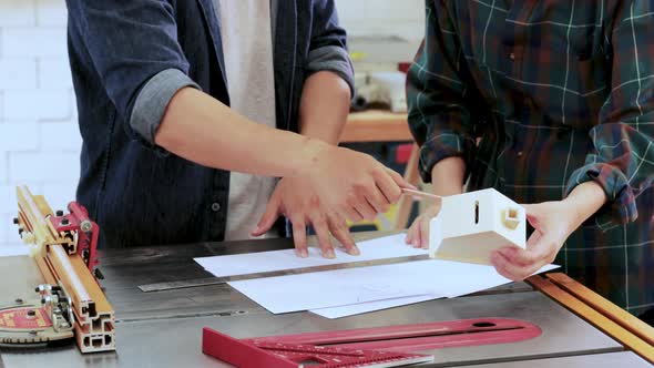 Close up of Man and Woman working with paperwork drawing in wood workshop