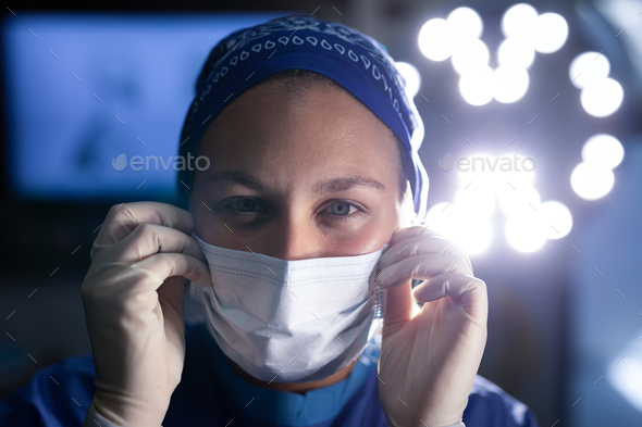 Female surgeon looking at the camera and putting on medical mask before operation