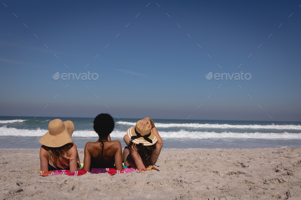 Young women lying and relaxing on a blanket at beach in front of the sea under the sunshine - Stock Photo - Images