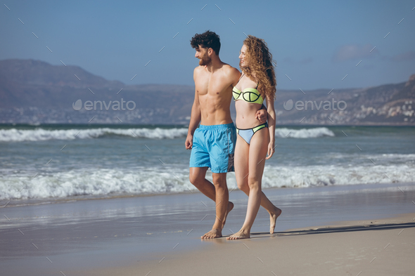 Couple Walking On The Beach While Male Has Arm Around Her Waist Stock Photo By Wavebreakmedia