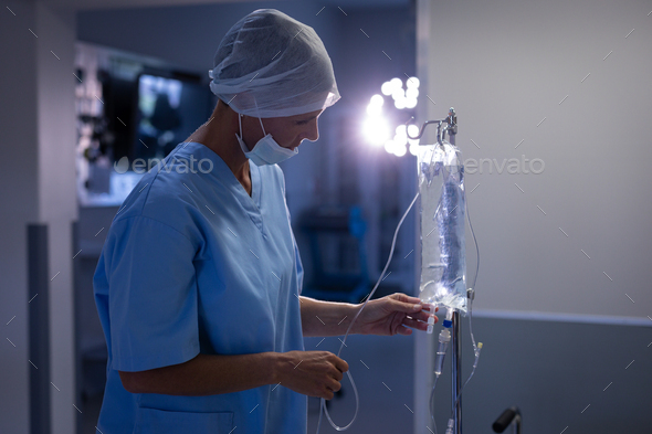 Side view of a Caucasian female surgeon checking intravenous therapy drip at hospital