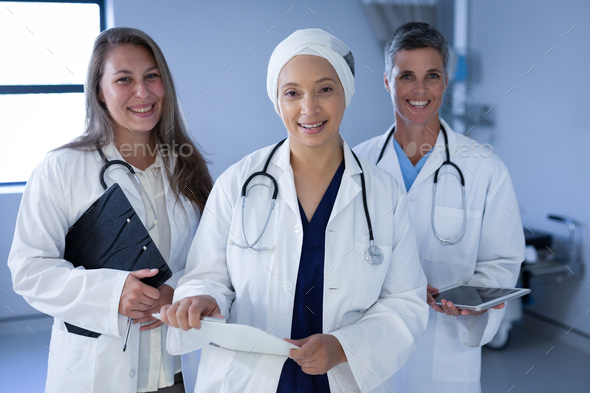 Female doctors standing in the hospital with stethoscope around the neck while holding folder - Stock Photo - Images