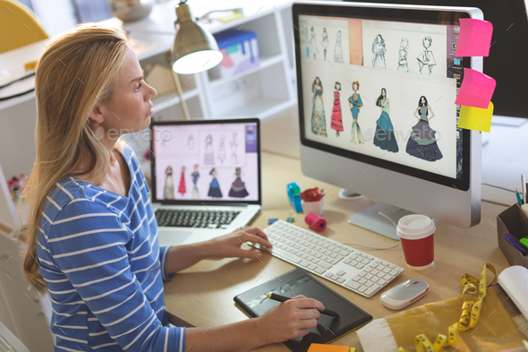 Female fashion designer using graphic tablet while working at desk in a modern office