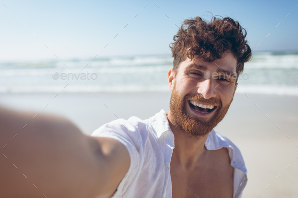 Man taking a selfie standing and at beach - Stock Photo - Images