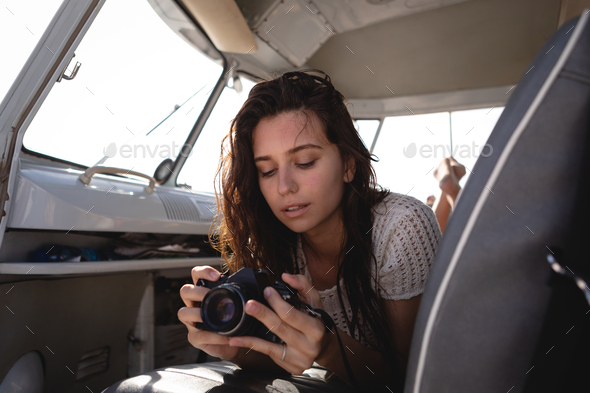 Woman using digital camera in camper van at beach