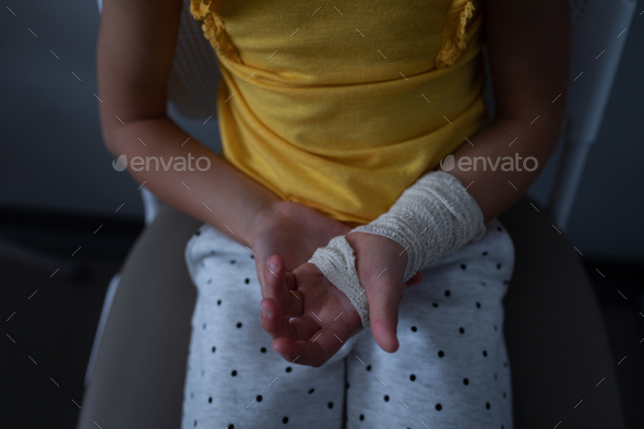 Mid Section Of Caucasian Girl Sitting With Fractured Hand In Clinic At