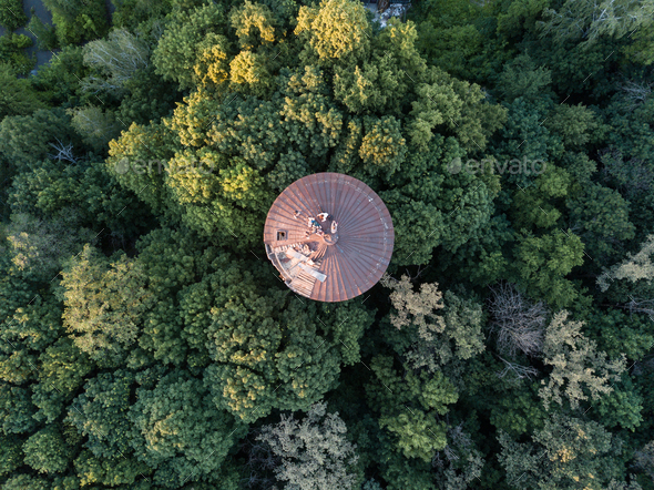 Top view of a round old roof with people around green trees. Aerial view from the drone