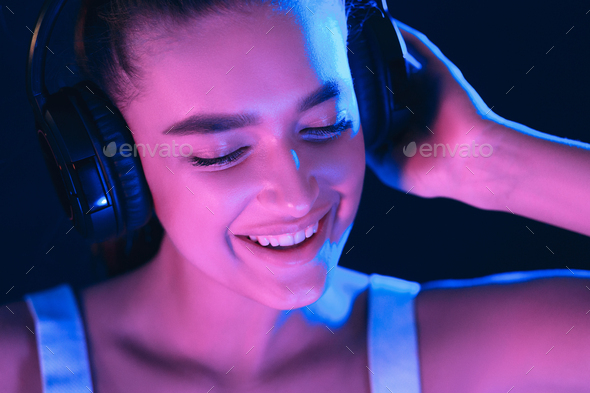DJ In Club. Woman in headset illuminated by neon lights
