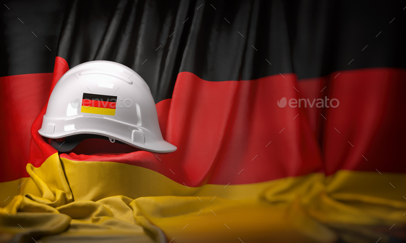 White hard hat laying over Germany flag. Construction and employ