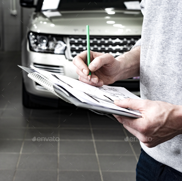 Mechanic writing to the clipboard at workshop warehouse - Stock Photo - Images