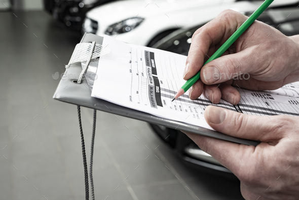 Mechanic writing to the clipboard at workshop warehouse - Stock Photo - Images
