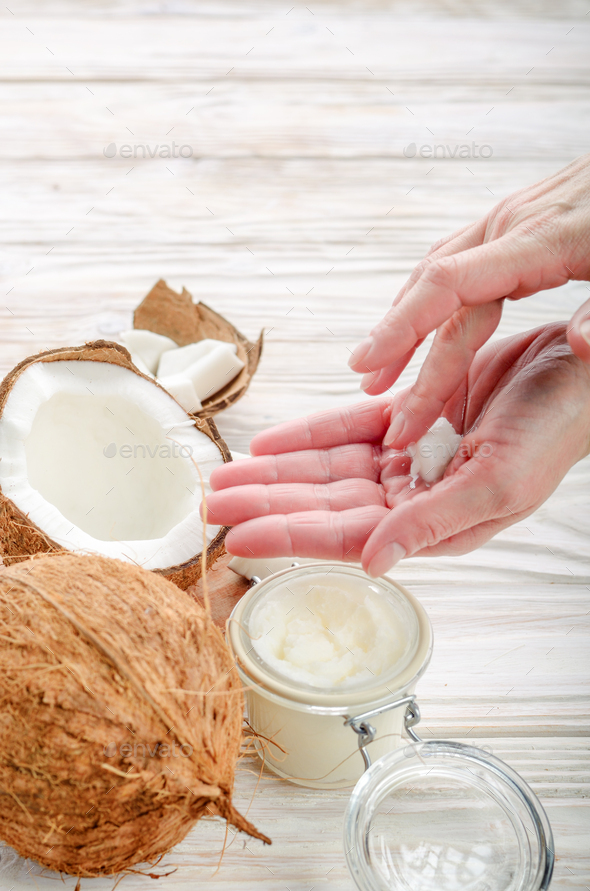 Coconut oil on human palm and in airtight glass jar with shell p - Stock Photo - Images