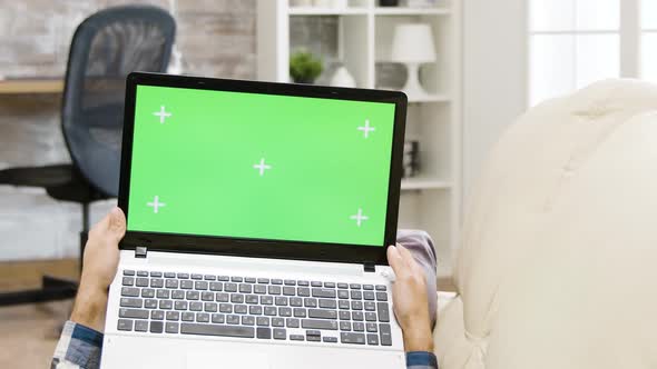 Zoom Out Parallax Shot of Man Holding a Green Screen Laptop alt
