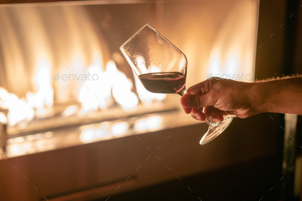 Hand Holding A Glass Of Red Whine Against Fire Pit Stock Photo By