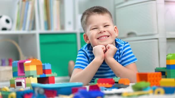 Preschool Boy is Playing with Different Colorful Toy Bricks in a Kindergarten alt