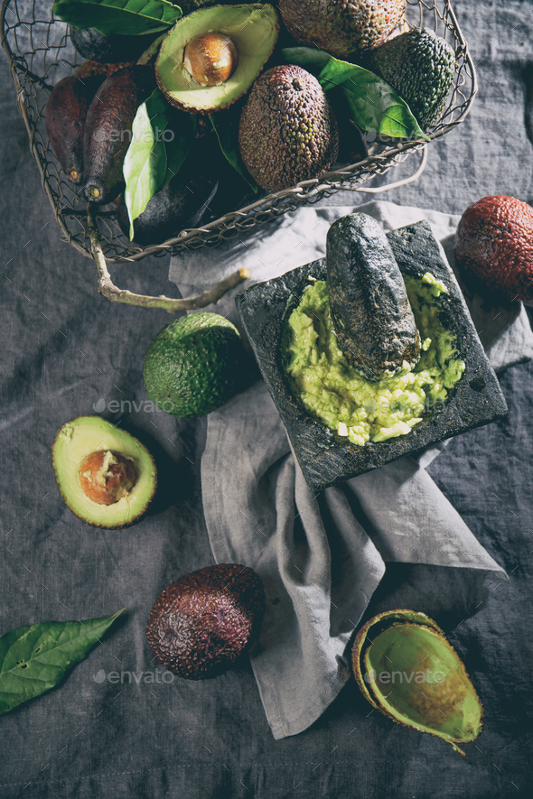 Mexican Guacamole Sauce in Stone Mortar, Full Basket with Avocado on Linen Tablecloth - Stock Photo - Images