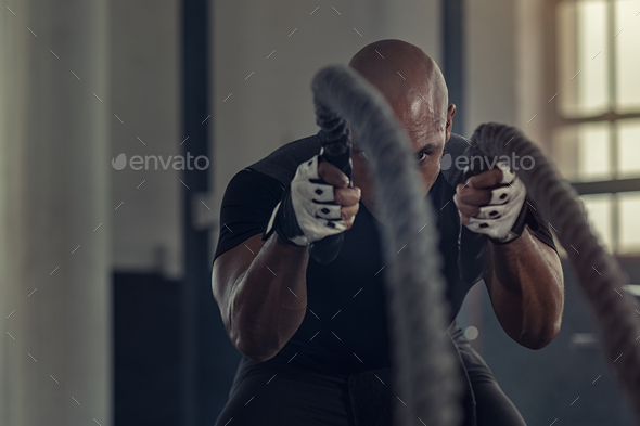 Black man doing intensive battle rope workout