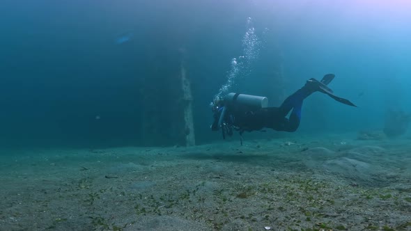 Scuba Diver Exploring Around Underside Pier Underwater Deep Ocean Scenery