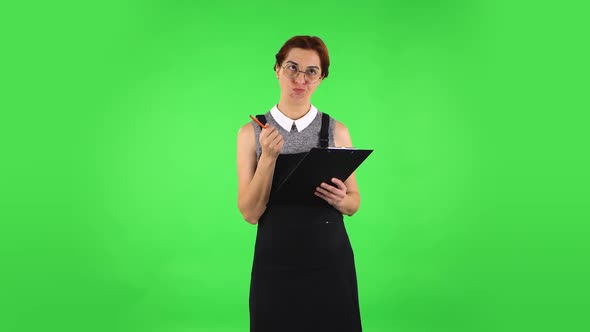 Funny Girl in Round Glasses Is Angrily Writing Plans at Black Folder with Pencil. Green Screen alt