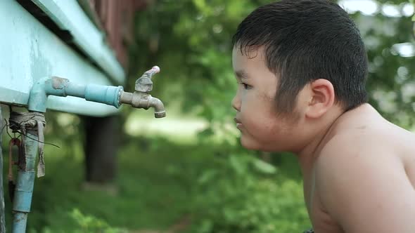 Slow motion of Asian boy drinking outdoors fresh water from tap, Saving water concept.