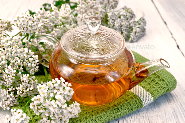 Tea with yarrow in glass teapot on napkin