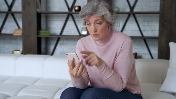 Sad Elderly Woman Sit on Sofa Hold Smartphone Feels Disappointed By Received Sms Bad News alt