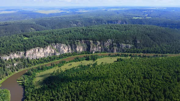 Bend of mountain river with rocky slope and a gentle shore covered with forests alt