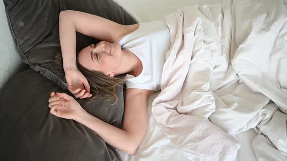 Attractive Smiling Young Woman Stretching in Bed Waking Up Alone, Awake After Healthy Sleep in Cozy