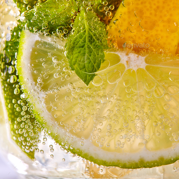 Macro photo of fresh slices of green lime, yellow lemon and mint leaf with bubbles in a glass - Stock Photo - Images