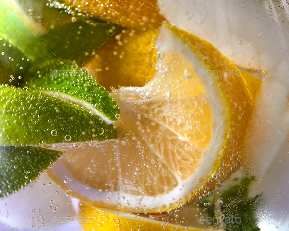 Macro photo of fresh lime and lemon slices with bubbles in the glass. Summer cold drink - Stock Photo - Images