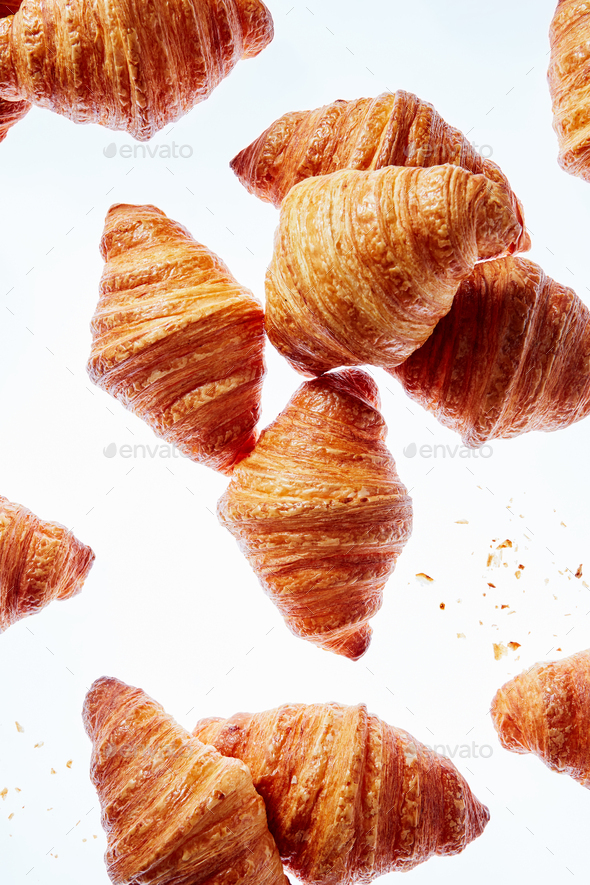 Falling fresh french croissants with crumbs on a light background - Stock Photo - Images