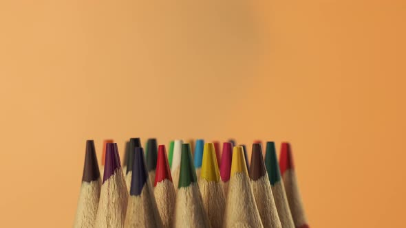 Education and back to school concept. Colored pencils on an orange background.  alt