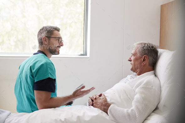 Surgeon Visiting And Talking With Senior Male Patient In Hospital Bed In Geriatric Unit - Stock Photo - Images