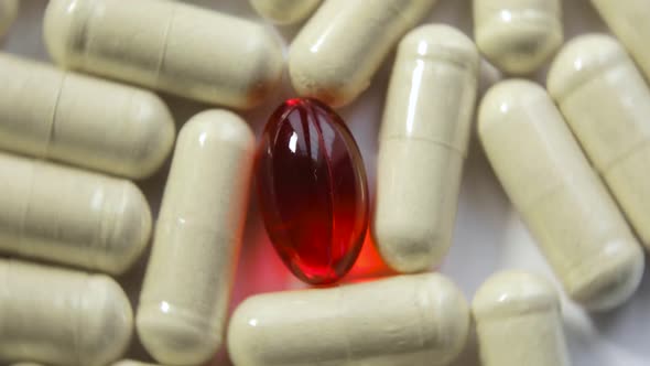 Rotating Yellow Pills and Red Gel Capsule on White Background Closeup View