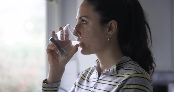 Cinematic shot of a woman at home drinking a glass of water