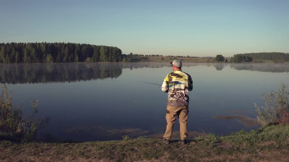 Man Fishing on Wooden Pier Near Lake