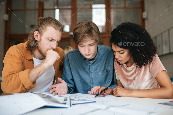 Two Boys With Blond Hair And Girl With Dark Curly Hair Studying