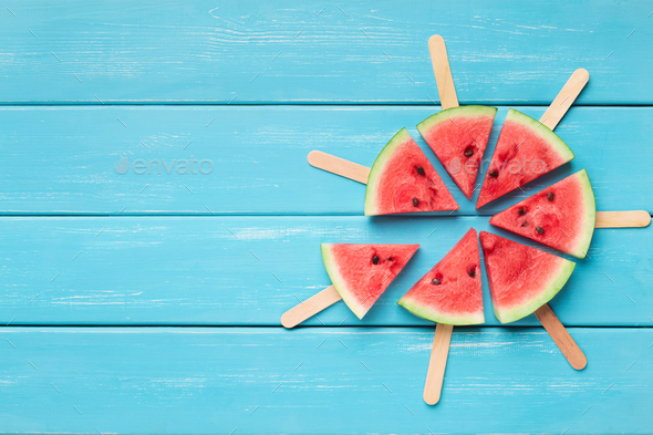 Watermelon popsicles circle on blue wooden background