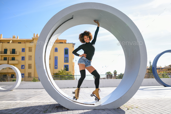 Black woman on roller skates riding outdoors on urban street - Stock Photo - Images